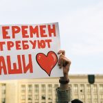 person holding red and white love is love print board